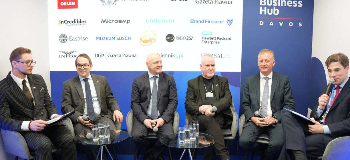 Grupa dobrze ubranych profesjonalistów w garniturach i marynarkach uśmiechających się i dzielących się wiedzą podczas wydarzenia VOS 2025. Polski Polish Business Hub reprezentowany przez ORLEN, InCredibles i innych. #PolskieBiznes #VOS2025 #DzielenieSięWiedzą