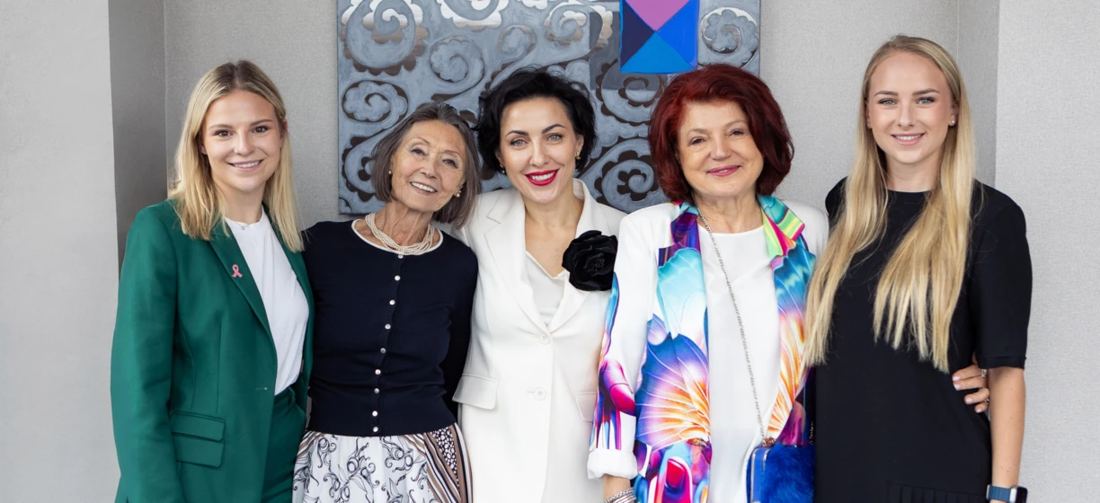 Kobieta z uśmiechem na twarzy, ubrana w stylowy bezrękawnik z tekstyliów. Promieniuje szczęściem na wydarzeniu modowym.