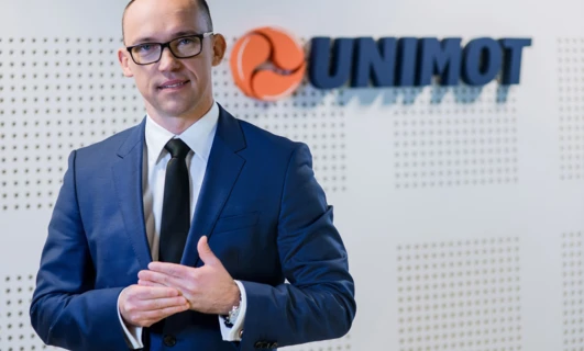 A white-collar worker in formal wear with a blazer and dress shirt showcasing the UNIMOT logo. Professional attire for a tech job.