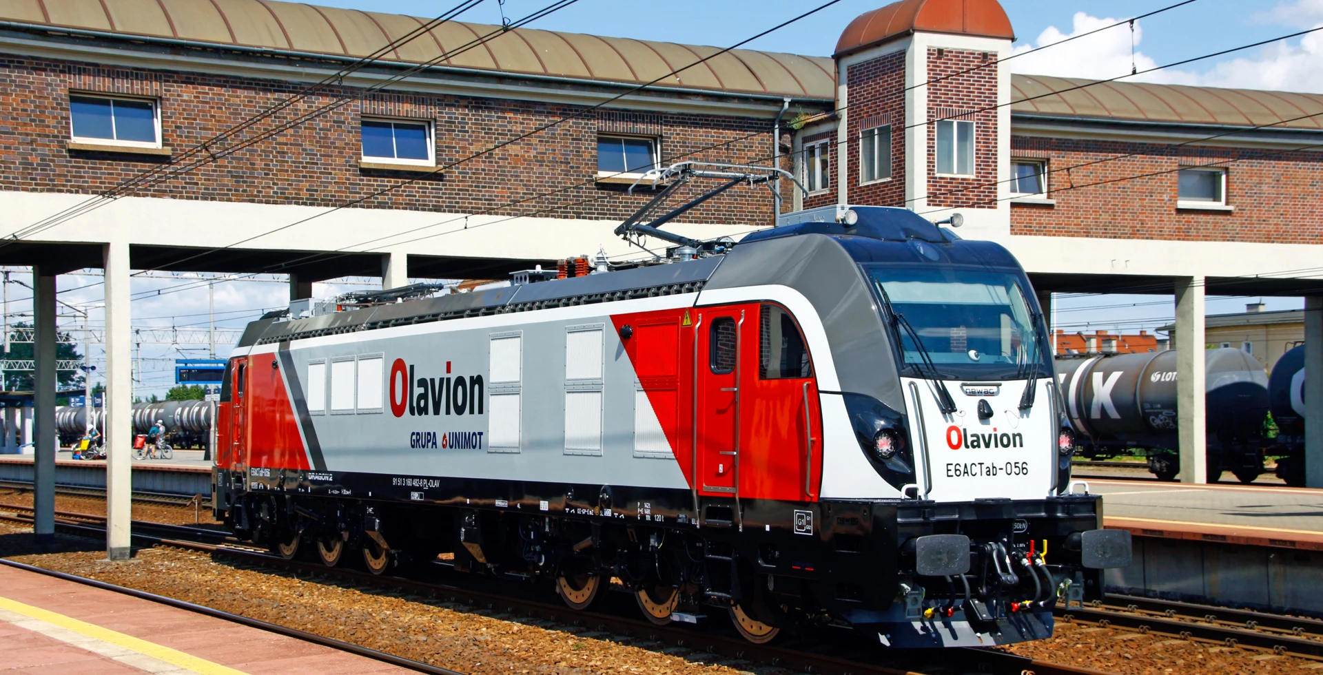 Lokomotywa na szynach kolejowych, symbolizująca transport kolejowy. Obraz autorstwa Tadeusza Kwaśniewskiego.