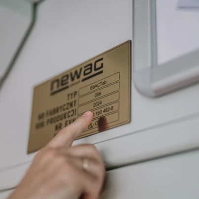 Obraz maszyny z etykietą "NEWAG" oraz innymi polskimi szczegółami produkcyjnymi. Słowa kluczowe to "maszyna," "newag," "produkcja" i "polski."